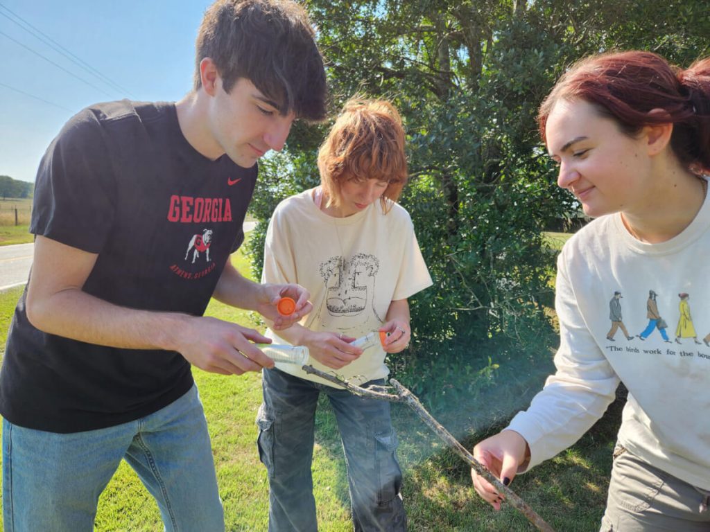 Co-authors of the study Kade Stewart, Caitlin Phelan and Alexa Schultz handle a Joro spider.